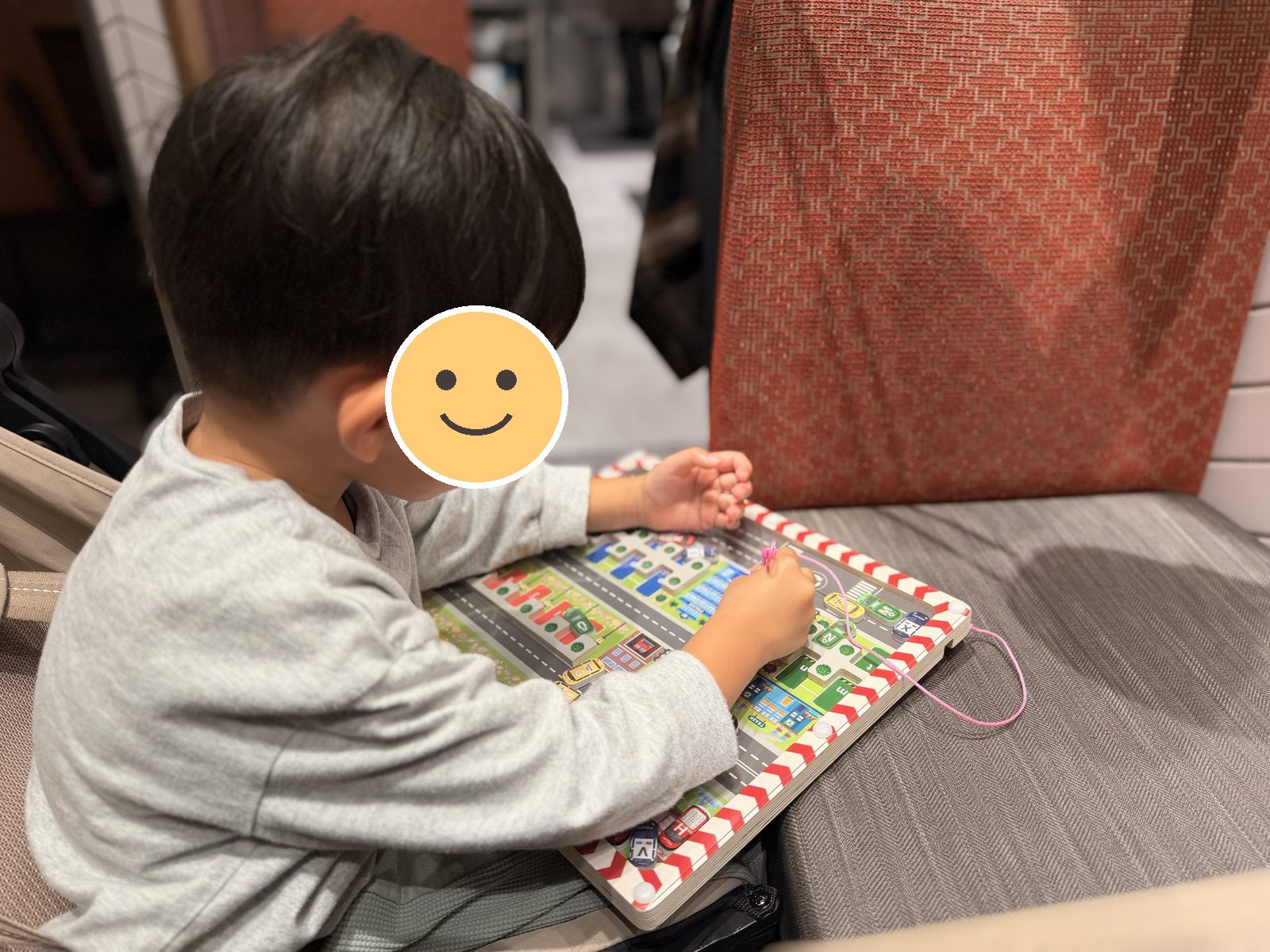 飛行機の座席で街のボードで遊ぶ息子