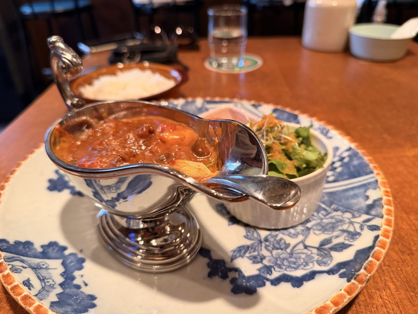 銀のソースポットに入ったエビのトマトココナッツカレー